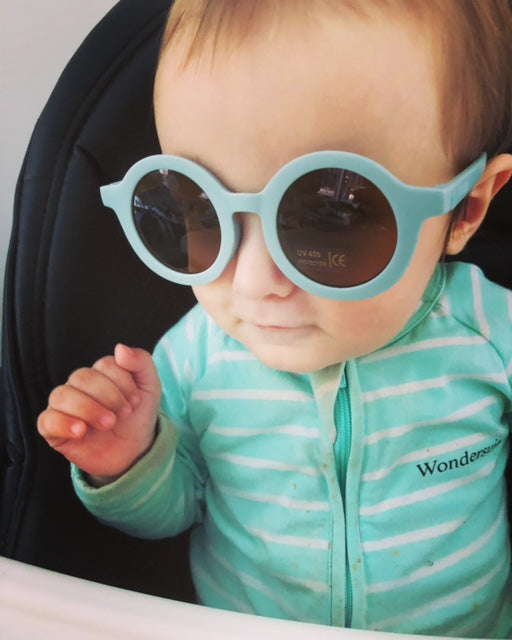 Baby wearing teeny round dusty blue UV400 sunglasses